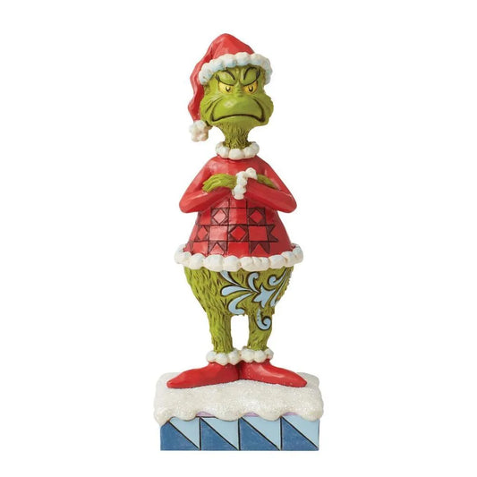 Front view of Grinch figurine in Santa hat and red diamond-patterned coat, arms folded, scowling, on a snowy blue-striped base 
