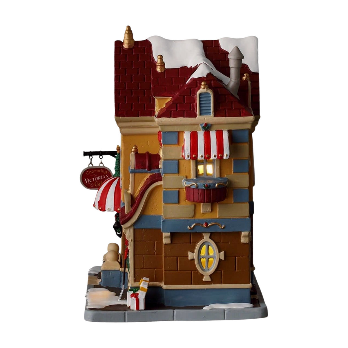 Left view of Lemax Father Christmas Gift Shop village building with Santa medallion, striped awning, lit display window, and snow