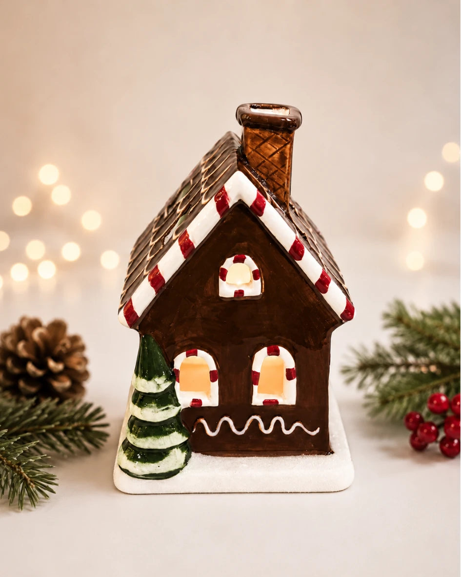 Ceramic gingerbread house tea light holder styled with Christmas tree and wrapped gift