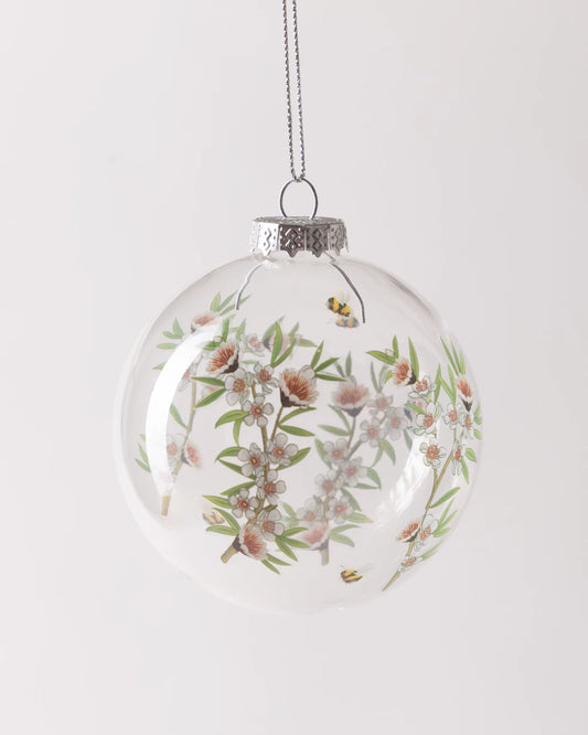 Clear glass bauble decorated with manuka flower and bee print design
