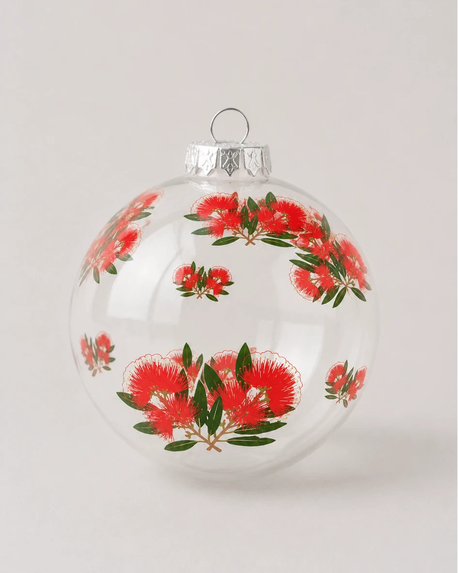 Clear glass bauble decorated with red pohutukawa flower and green leaf print design