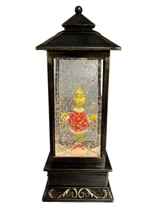 Brass lantern-style snow globe featuring the Grinch in a red Santa outfit surrounded by swirling glitter