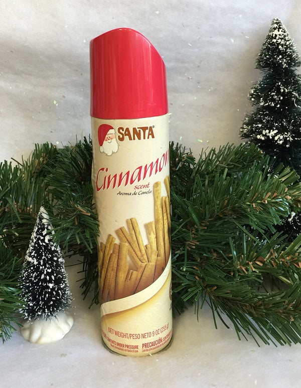 Cinnamon-scented spray can with Santa brand logo, surrounded by Christmas trees and decorations on a snowy background.