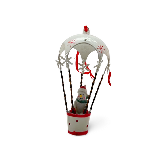 Three metal hot air balloon Christmas ornaments in red, green, and white, each with a festive character—Santa, snowman, or reindeer—riding in the basket with hanging ribbon.