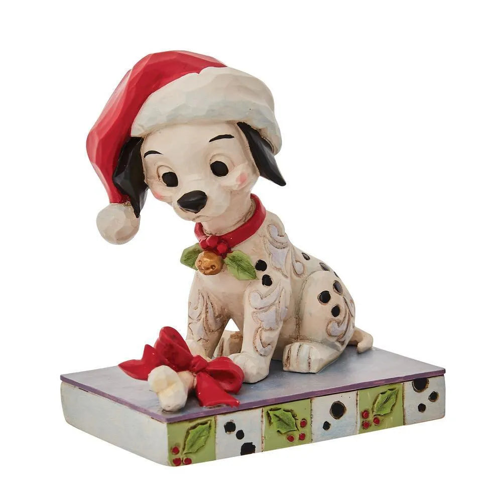 Side view of a Dalmatian puppy figurine in Santa hat, red collar with bell and holly, bone gift with red bow, holly-spot base