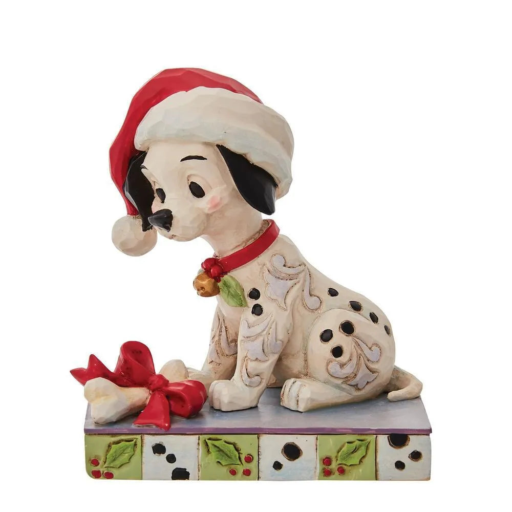Front view of a Dalmatian puppy figurine in a Santa hat, red collar with bell and holly, bone gift with red bow, holly base