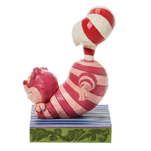 Side view of Cheshire Cat Christmas figurine lying on its side, grinning, with a candy cane tail curling upward above