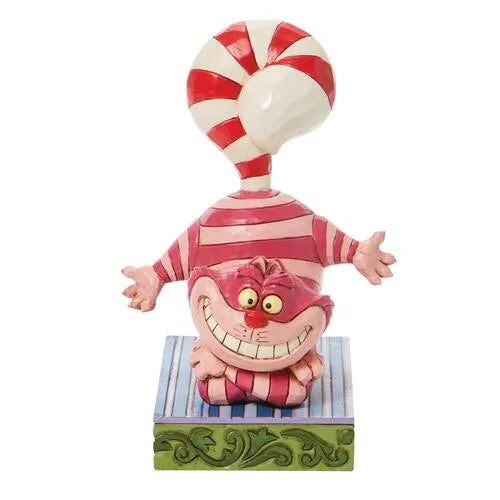 Front view of Cheshire Cat Christmas figurine, wide grin, arms spread, with a candy cane tail arching above on a striped base