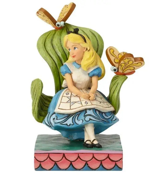 Alice in Wonderland figurine seated among large green leaves with two butterfly creatures, blue scrollwork dress, pink scale base