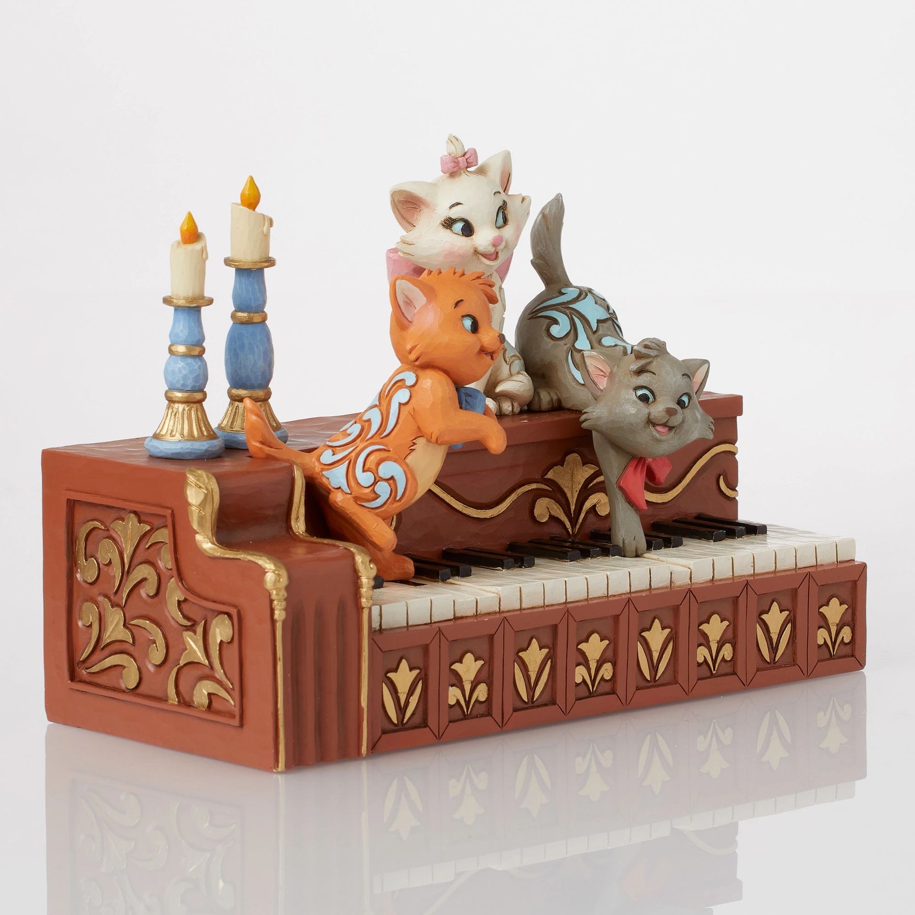 Marie, Toulouse and Berlioz figurine on piano keys with blue candlesticks, gold scrollwork piano body detail