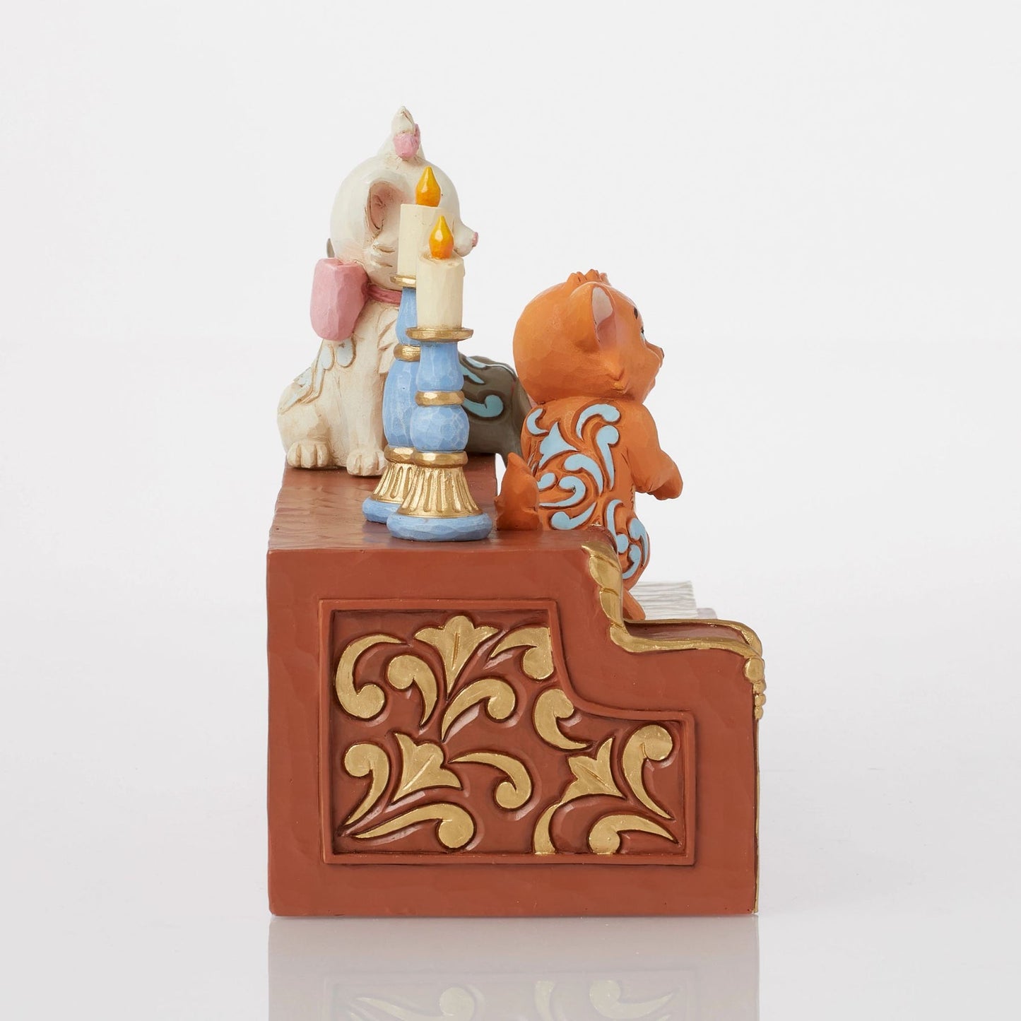Side view of Aristocats kitten figurine trio on piano keys, blue candlestick and gold scrollwork piano detail