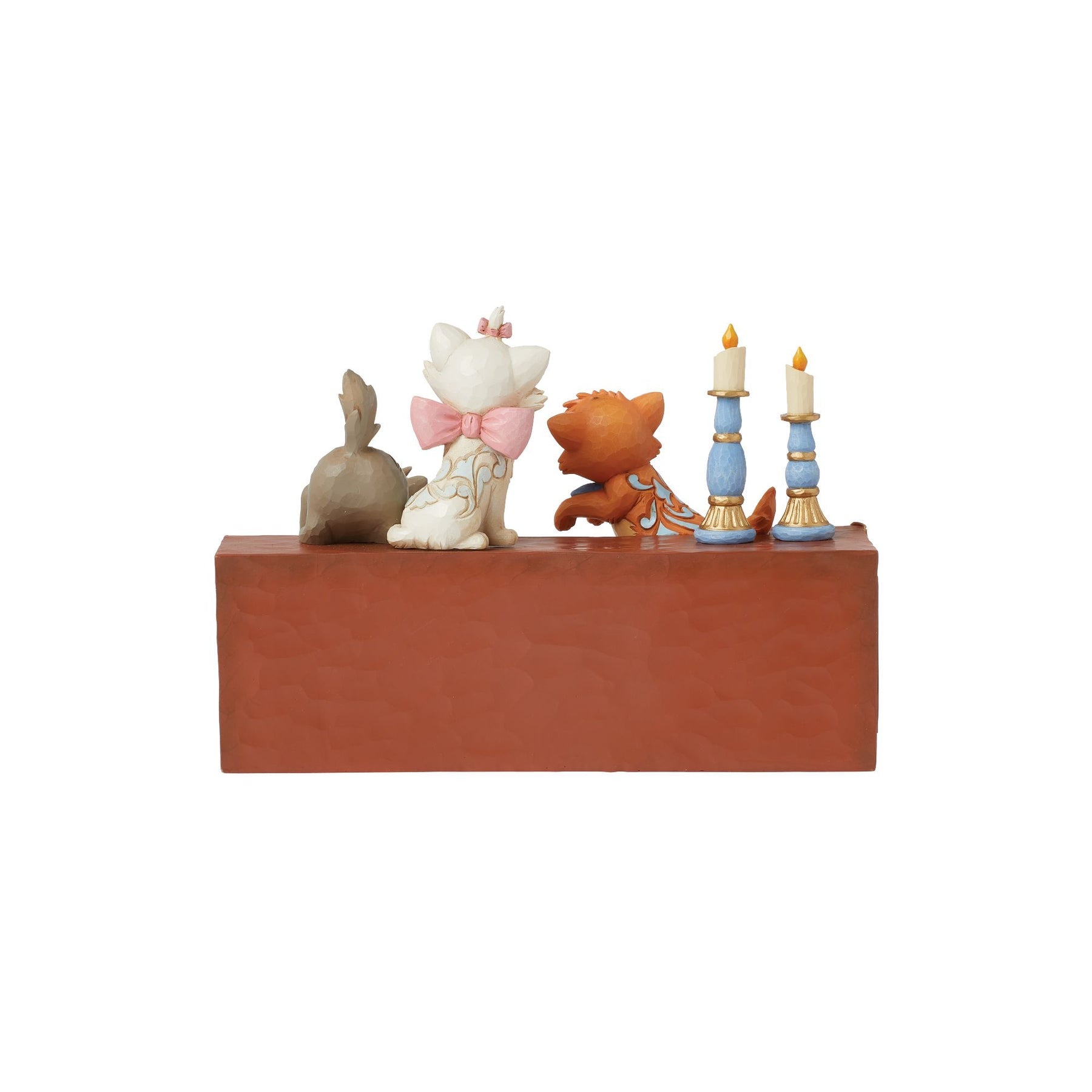 Rear view of Aristocats kitten figurine trio on piano top with blue candlesticks, gold scrollwork piano detail
