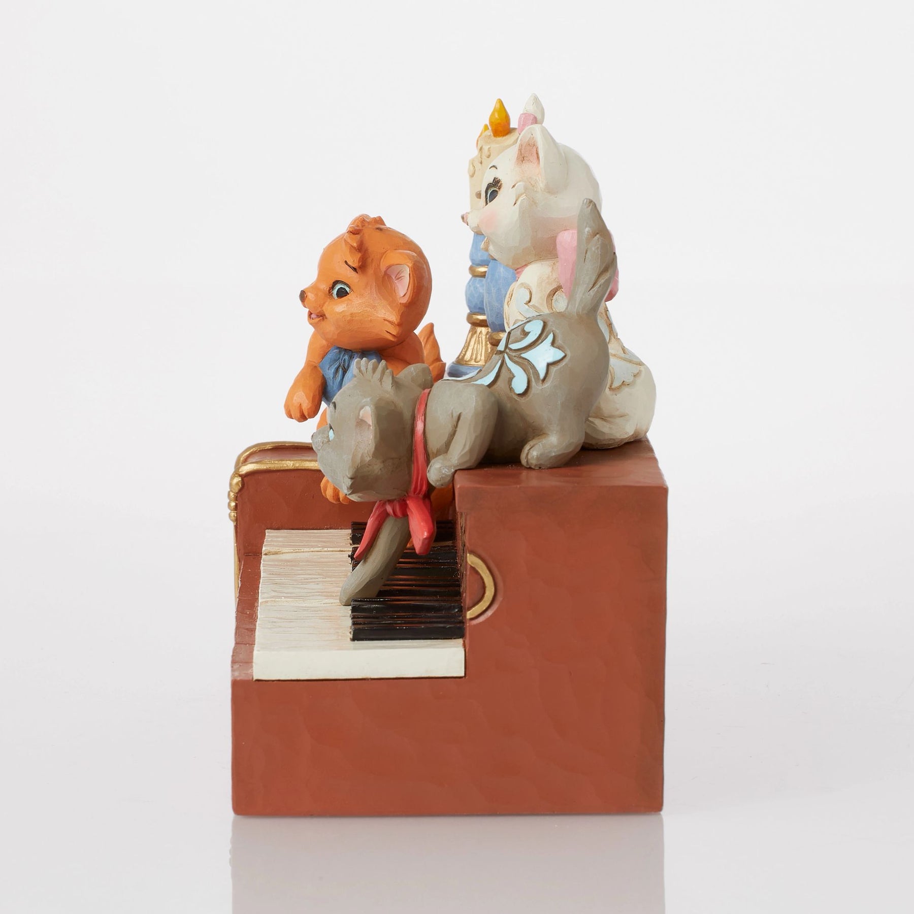 Side view of Aristocats piano figurine showing gold scrollwork piano body, blue candlestick and kitten detail