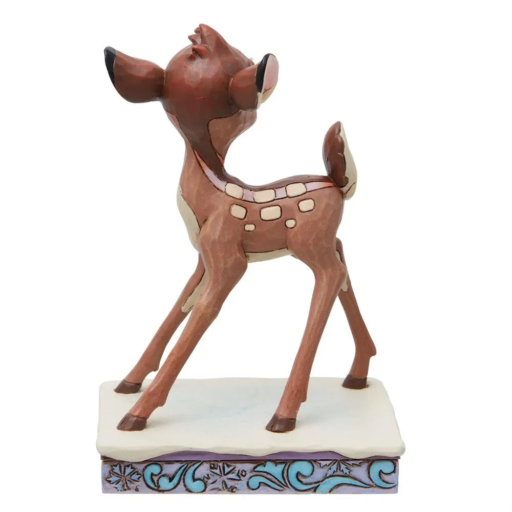 Side view of a Bambi fawn figurine with spotted markings, gazing upward, on a snowflake-patterned decorative base