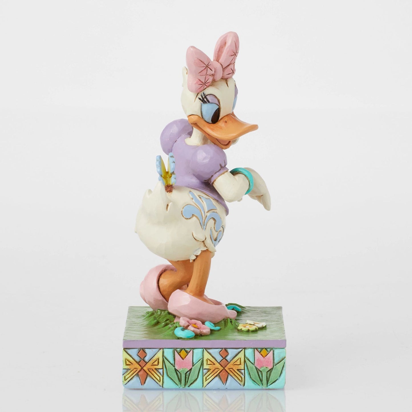 Daisy Duck figurine with yellow butterfly on hand, pink bow, purple top, scrollwork body detail, floral tulip base