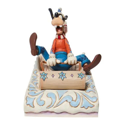 Front view of Goofy Christmas figurine seated in a folk art sled with snowflake detail, blue scrollwork base, legs outstretched