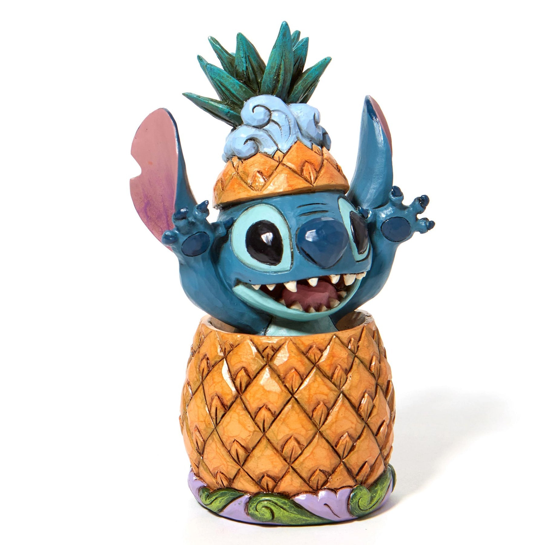 Stitch in pineapple figurine front view, mouth open and arms raised, on a floral scroll display base with plaque