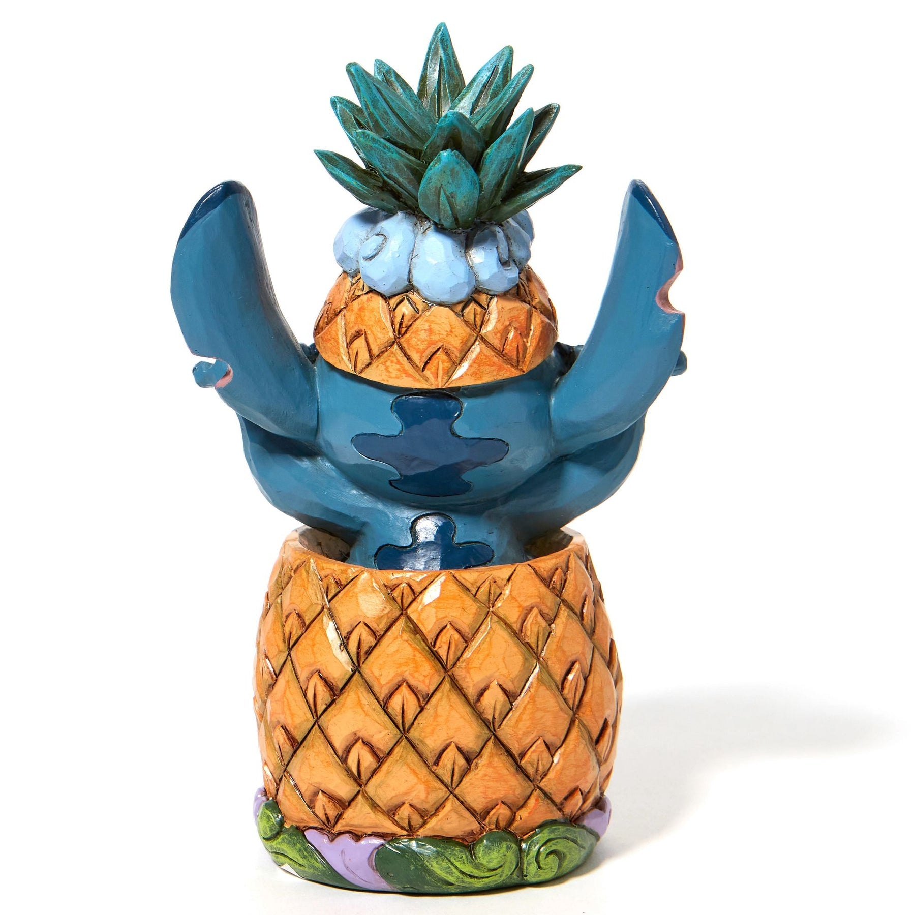 Rear view of Stitch figurine popping out of a pineapple with arms raised, pineapple crown on head, on scroll base