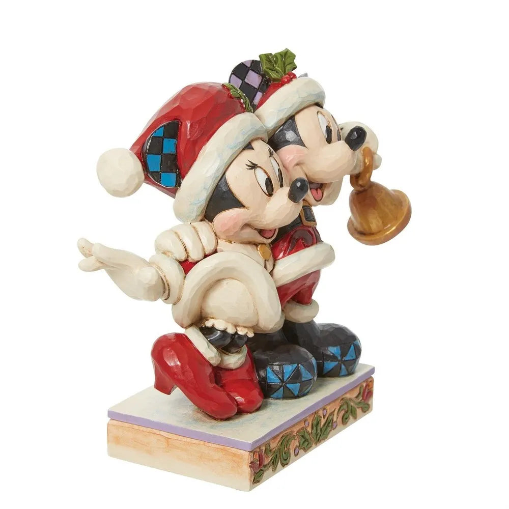 Side view of Mickey and Minnie Mouse Santa figurines close together, Mickey holding a gold bell, on a holly-painted base