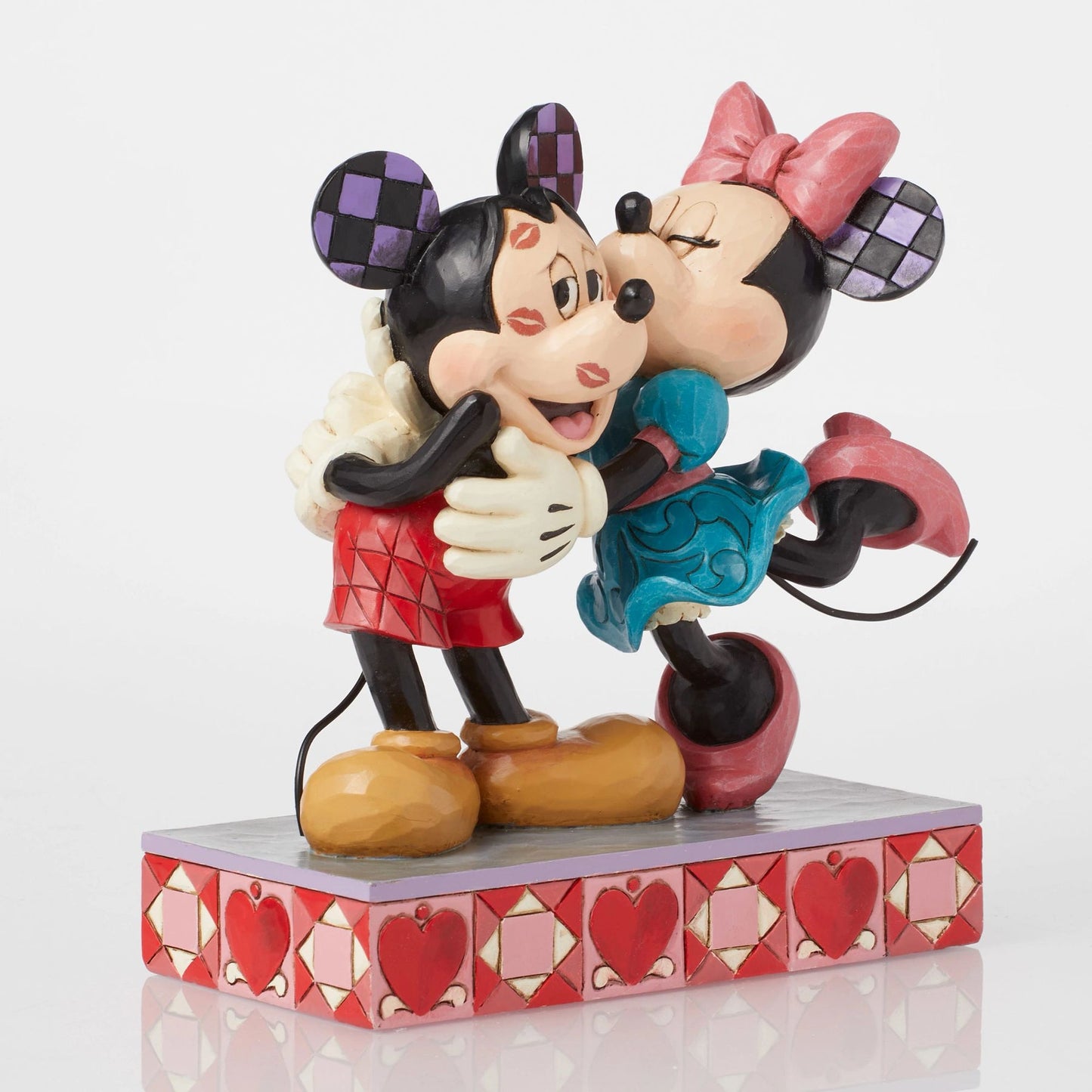Front view of Mickey and Minnie Mouse figurine, Minnie kissing Mickey's cheek, checkered ears, heart base
