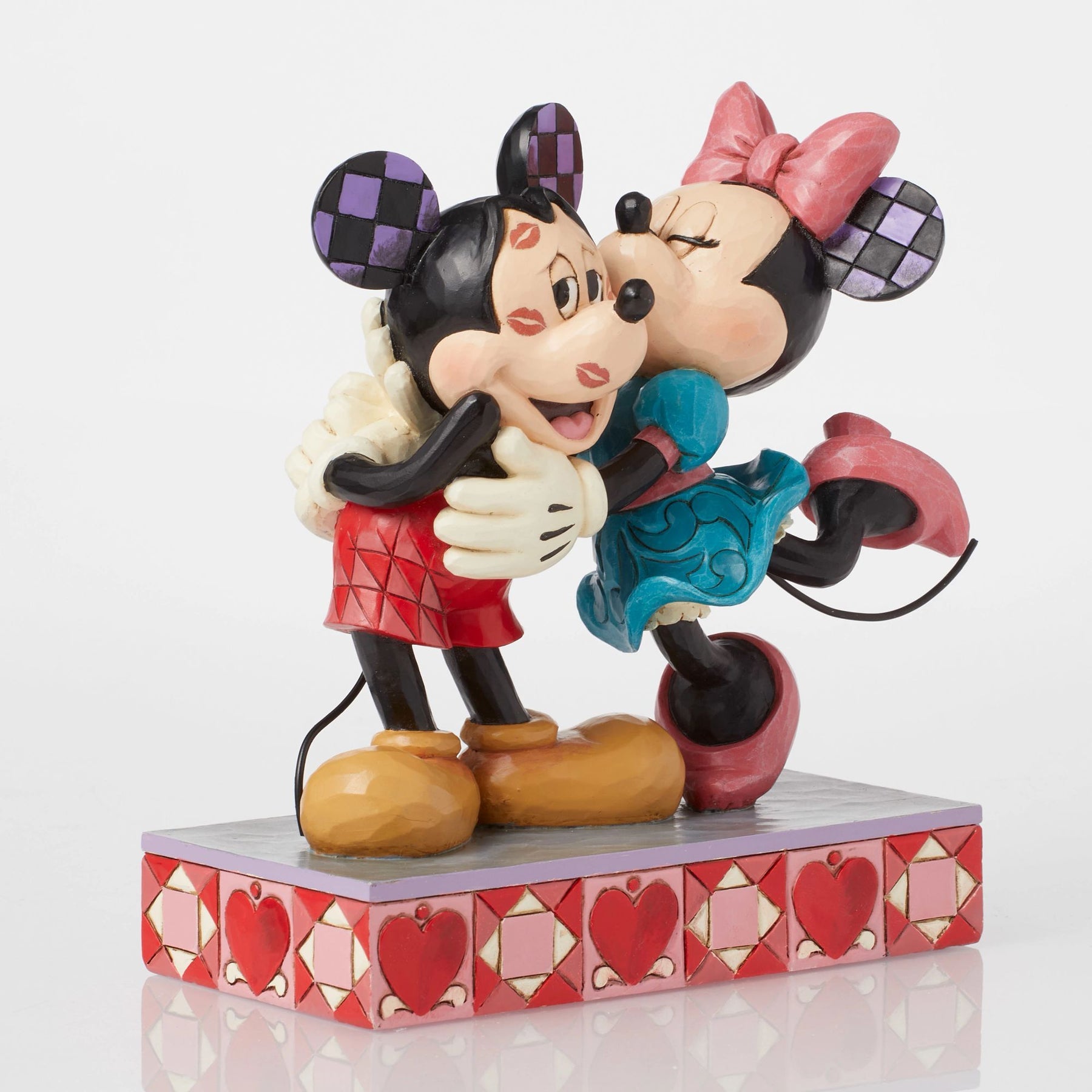 Front view of Mickey and Minnie Mouse figurine, Minnie kissing Mickey's cheek, checkered ears, heart base