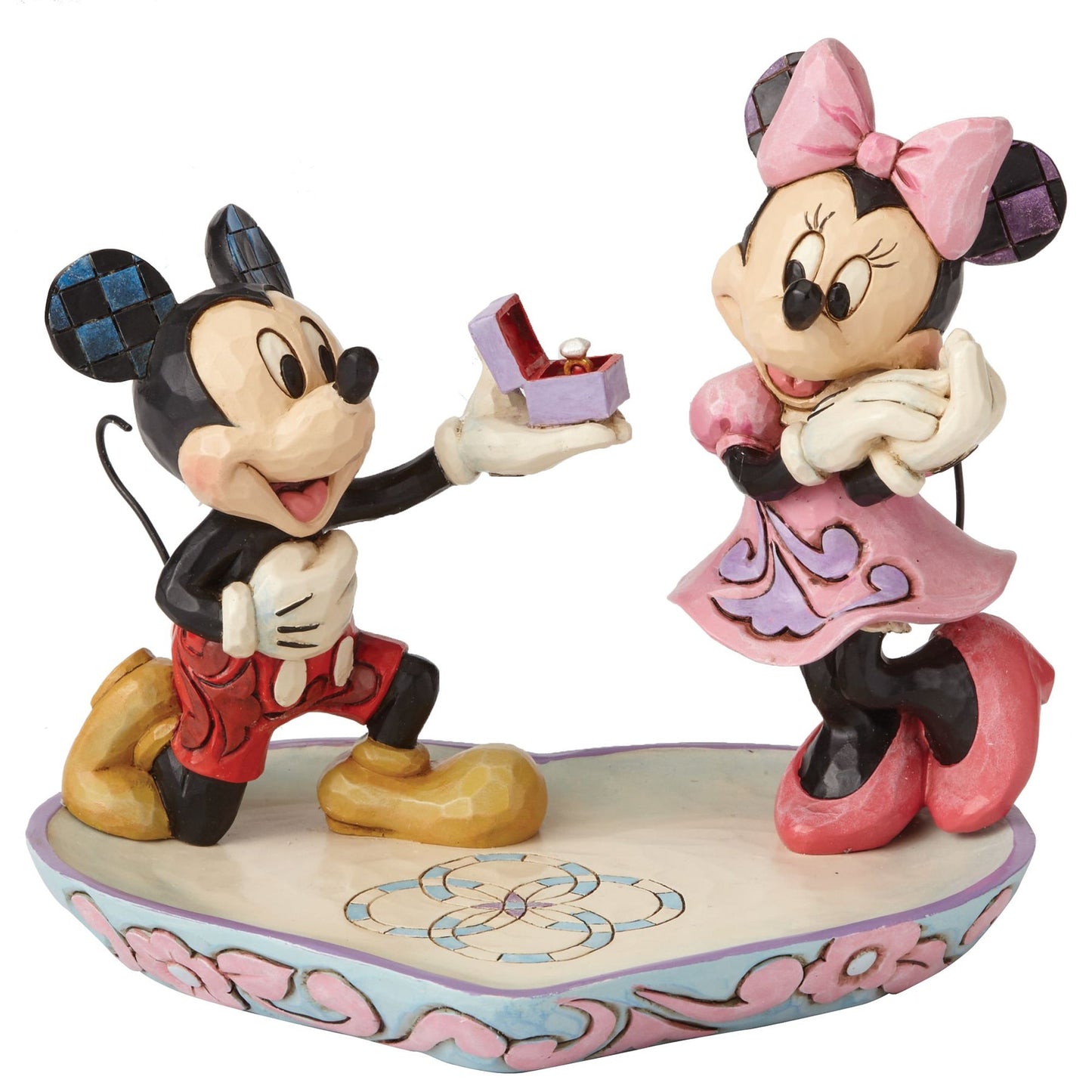 Mickey Mouse on one knee presenting a ring box to Minnie, on a heart-shaped base with pink floral scrollwork border