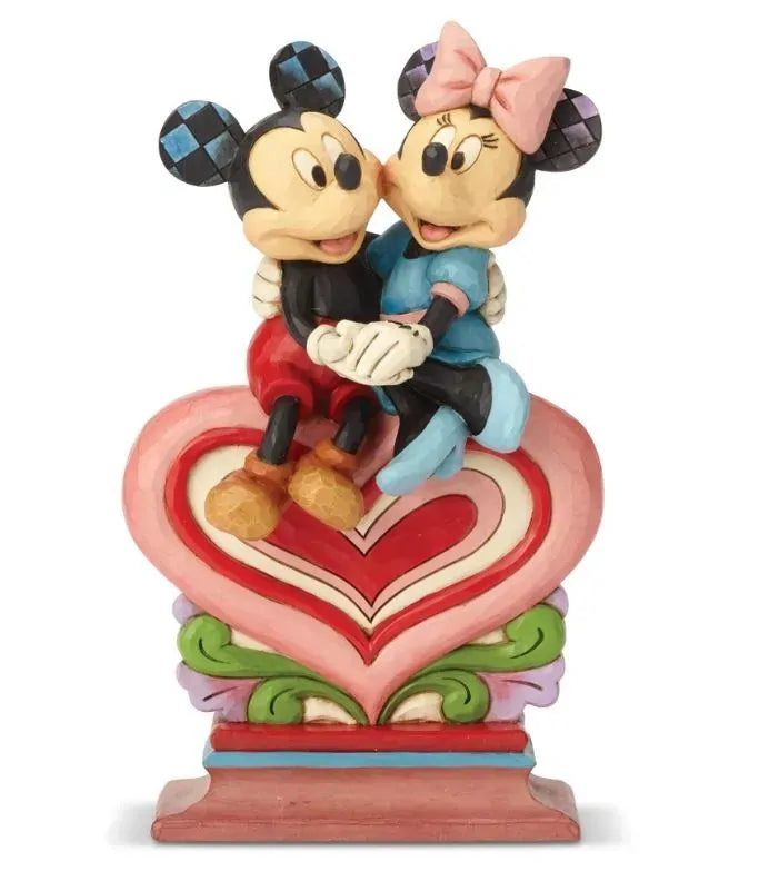 Mickey and Minnie Mouse sitting together on a layered heart pedestal figurine, holding hands, on a colourful scrollwork base