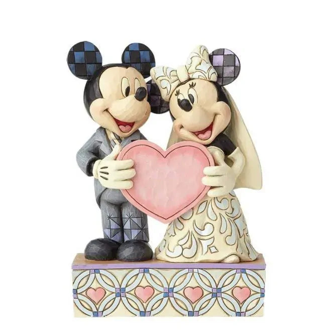 Mickey in grey suit and Minnie in scrollwork bridal gown holding a large pink heart together, on a heart pattern painted base