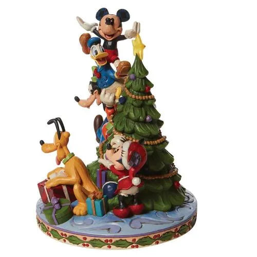Side view of Mickey, Donald, Goofy, Pluto and Minnie figurine decorating a Christmas tree, with wrapped gifts around the base.