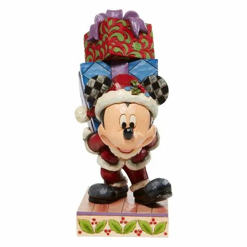 Front view of Mickey Mouse Christmas figurine in Santa outfit carrying stacked gifts, on a holly-decorated base. 