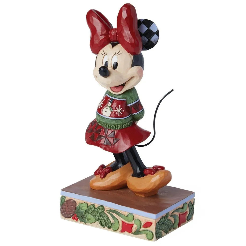 Side view of a Minnie Mouse Christmas figurine in a red bow, snowman sweater, and geometric skirt on a pinecone and holly base.