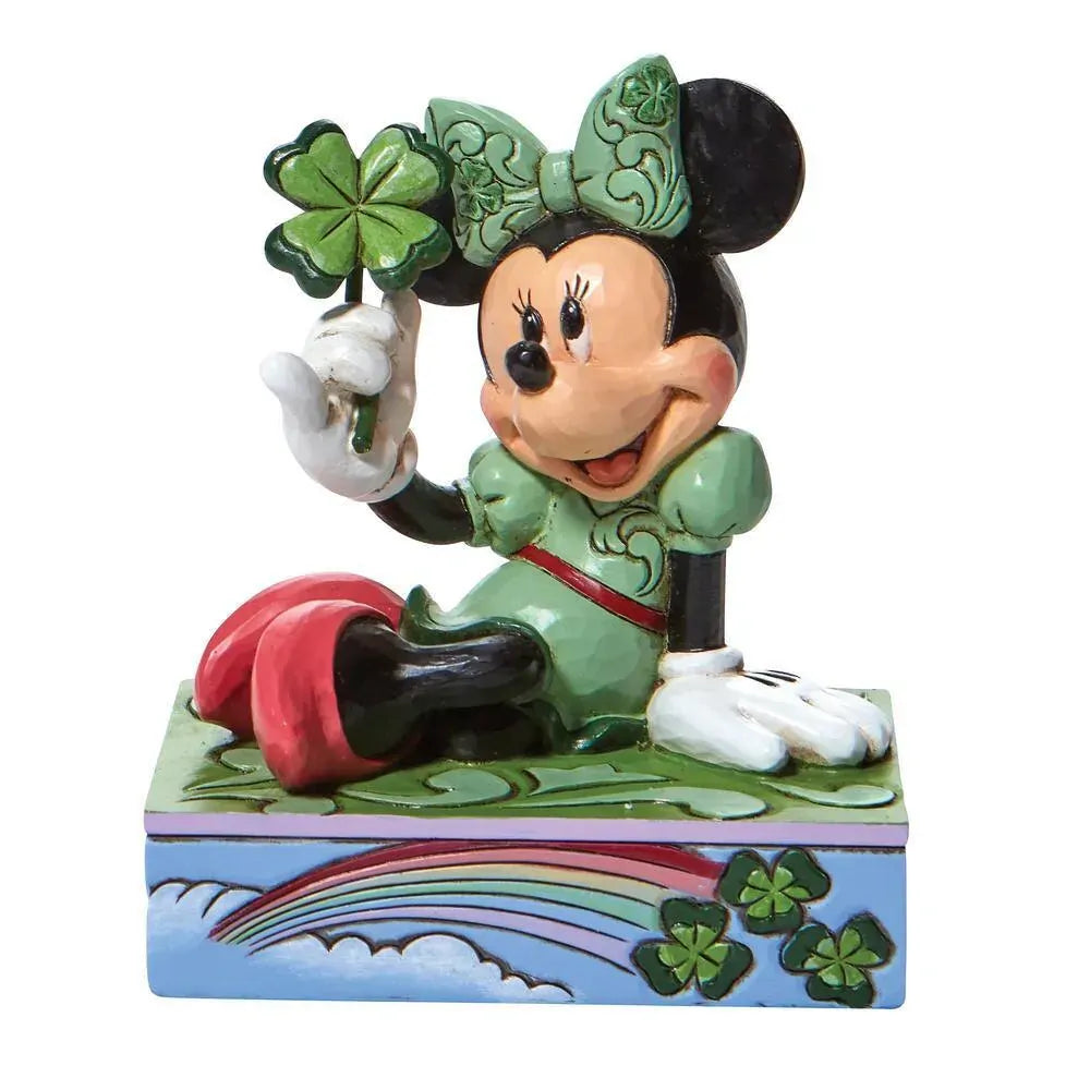 Minnie Mouse figurine in green outfit and bow, holding a four-leaf clover, seated on a rainbow and shamrock painted base 