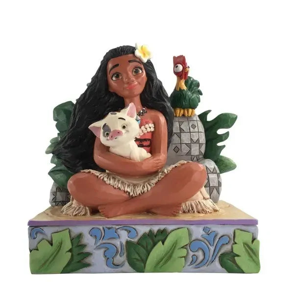 Moana figurine seated cross-legged holding Pua, with Hei Hei perched behind, surrounded by tropical foliage on a leaf-decorated base