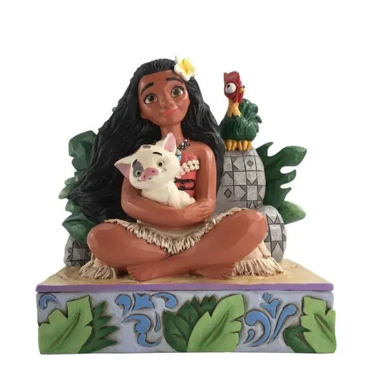 Moana figurine seated cross-legged holding Pua, with Hei Hei perched behind, surrounded by tropical foliage on a leaf-decorated base