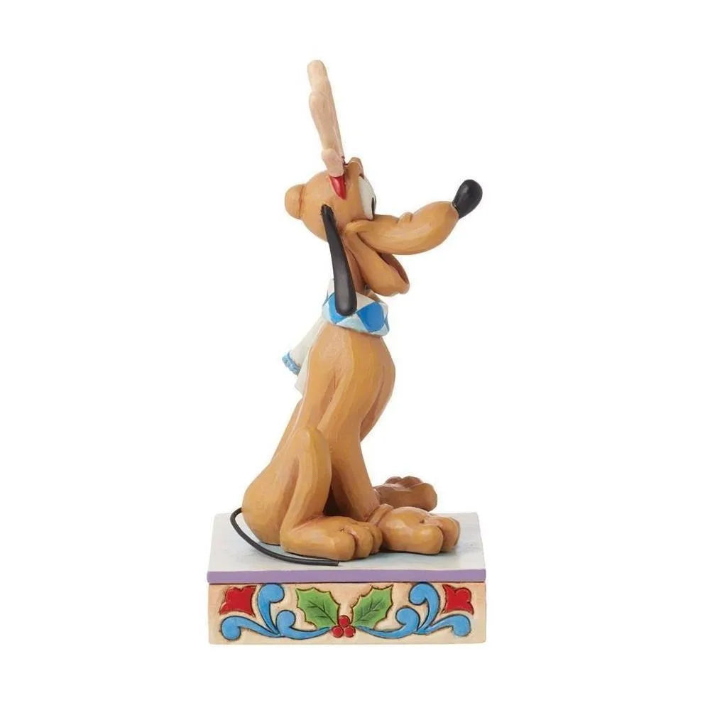 Side view of a Pluto Christmas figurine with reindeer antlers and blue argyle scarf, on a holly-decorated scrollwork base.