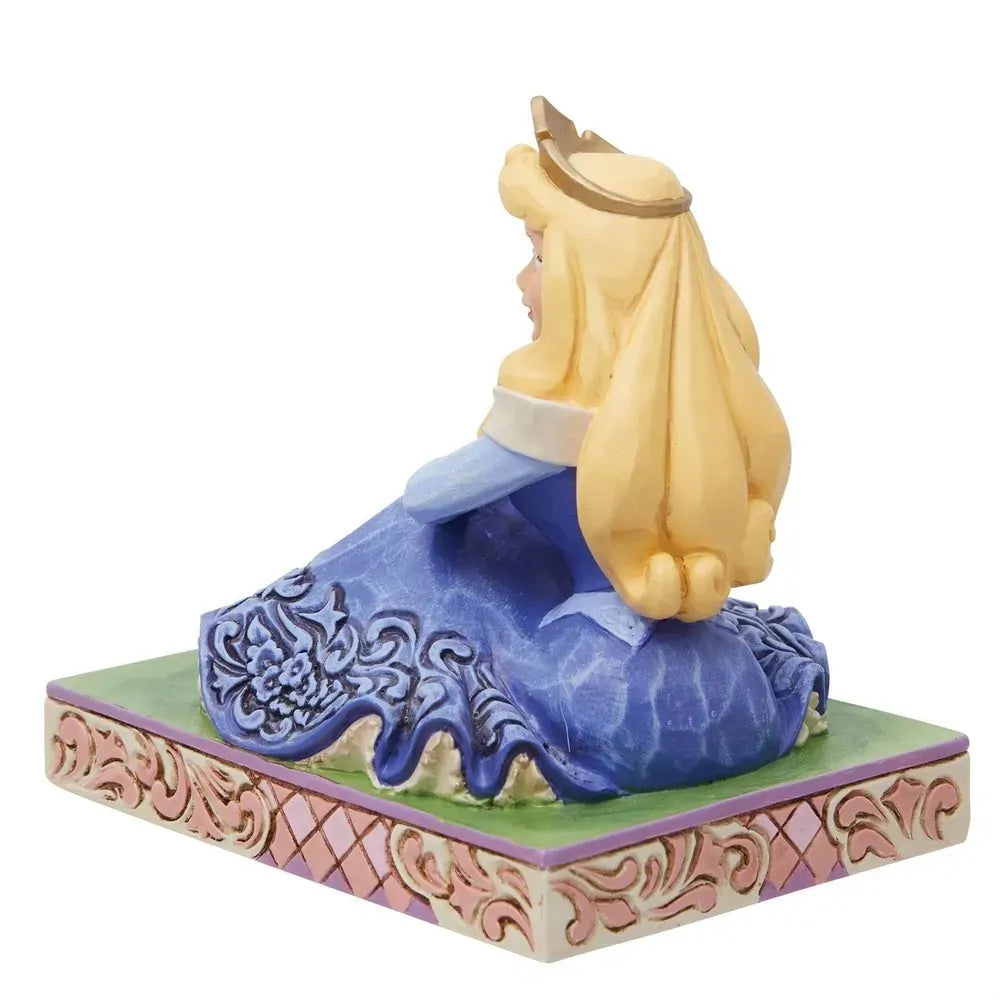 Rear view of Aurora figurine seated in blue gown with floral scrollwork skirt, gold crown, pink lattice base
