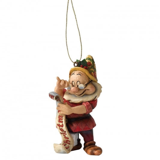 Doc dwarf hanging ornament with folk art detailing, holding a Christmas scroll and pointing, wearing glasses and a holly-topped hat