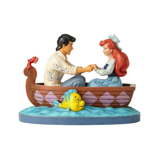 Ariel and Prince Eric figurine holding hands in a rowboat, with Flounder in the water and Sebastian on the stern