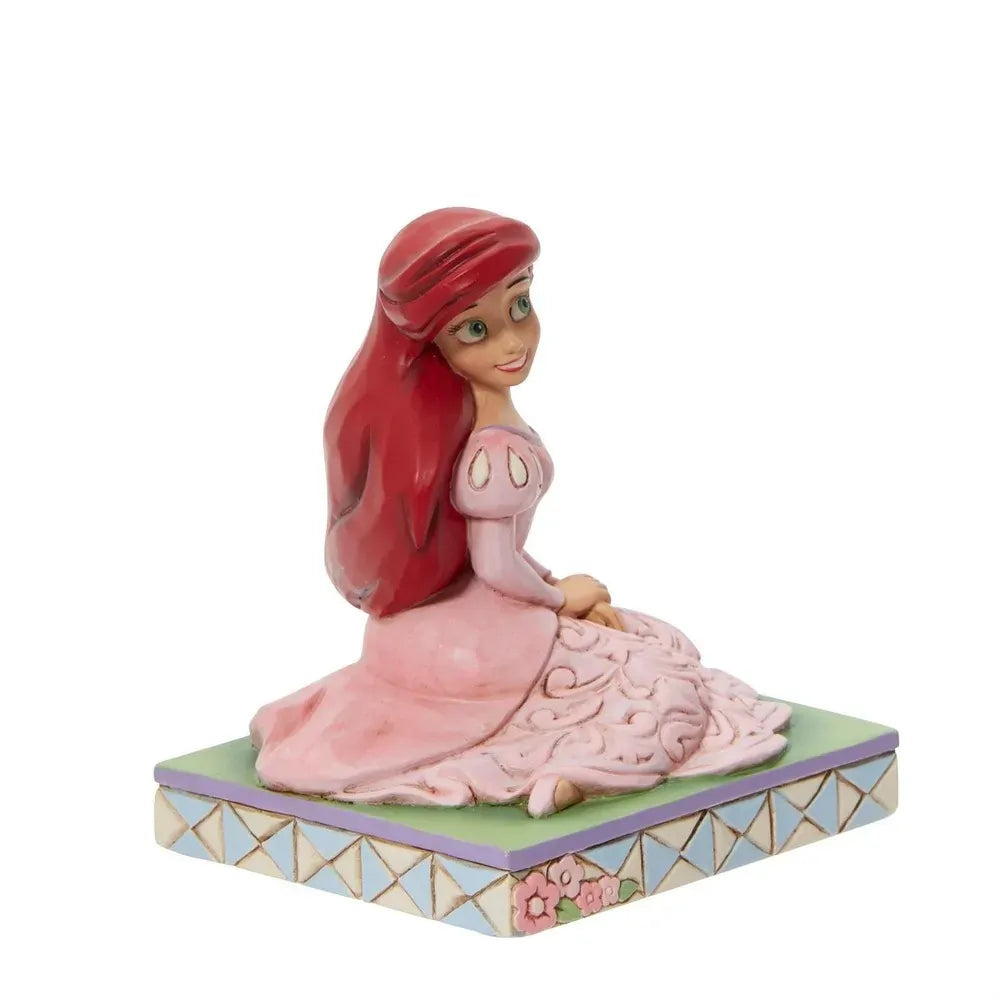 Side view of Ariel figurine in pink gown with scrollwork detail, red hair, smiling, floral lattice base