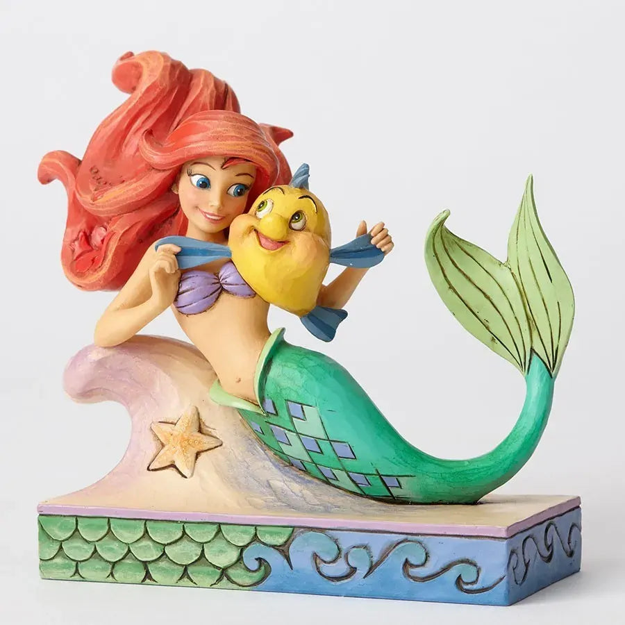 Ariel holding Flounder figurine, green diamond-patterned tail on a painted wave base with starfish and scale detailing