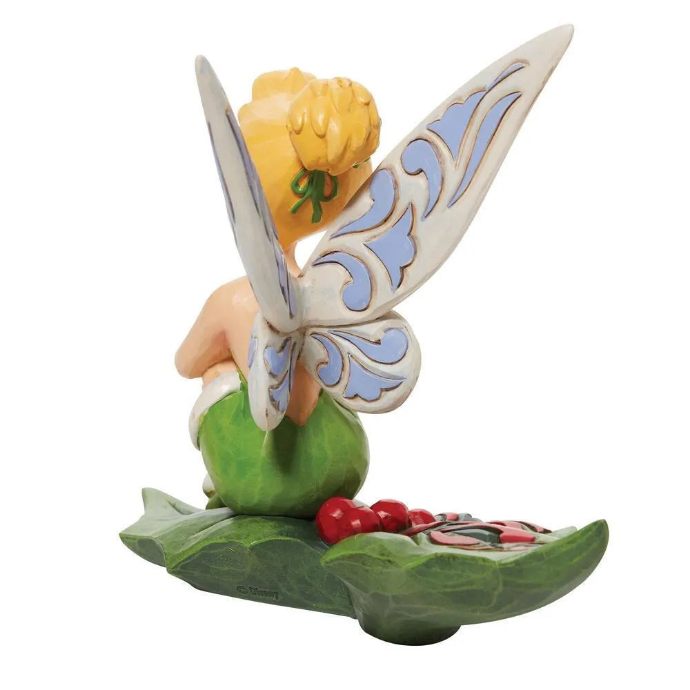 Rear view of Tinker Bell figurine seated on a holly leaf base with red berries, scrollwork wings with blue detail 