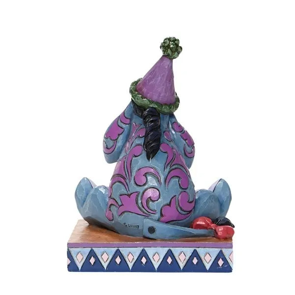 Rear view of Eeyore figurine showing scroll-painted back detail, party hat, and deflated balloon on the base