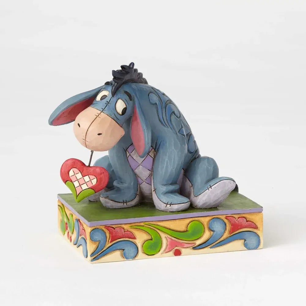 Eeyore from Winnie the Pooh figurine seated with a small red heart, blue scrollwork body detail on a colourful painted base