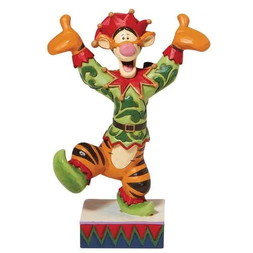 Front view of Tigger dressed as a Christmas elf figurine, arms raised wide with a jester-style hat, on a decorative base