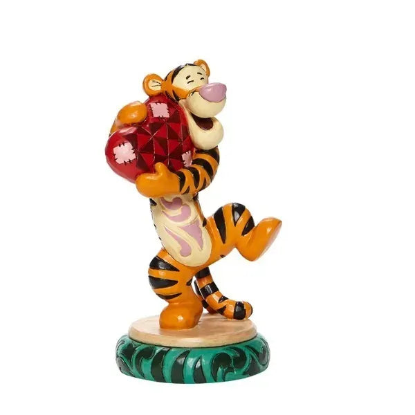 Tigger figurine front view, hugging a red patterned heart with a wide smile, on a green scroll round base