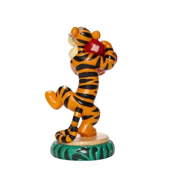 Rear view of Tigger figurine holding a red heart aloft, showing full stripe detail, on a green round base 