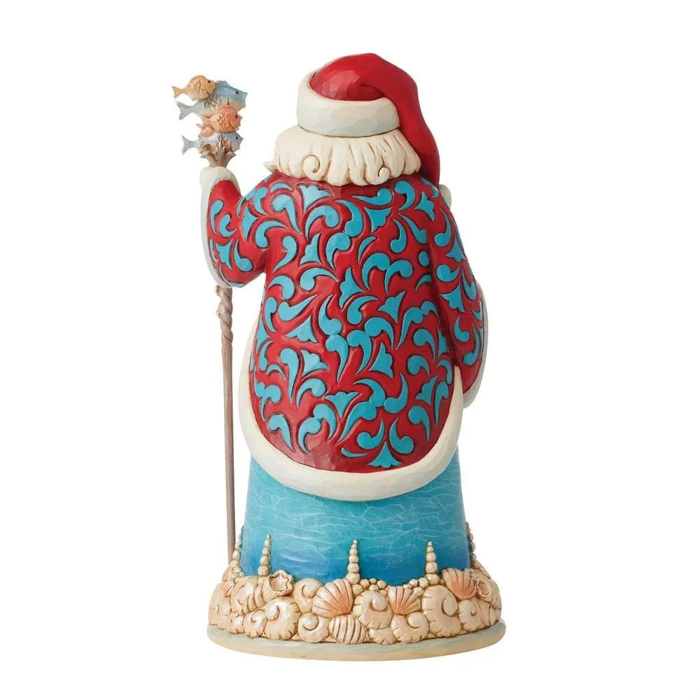 Rear view of a coastal Santa figurine in a red and teal scrollwork coat, holding a fish-topped staff, seashell-decorated base