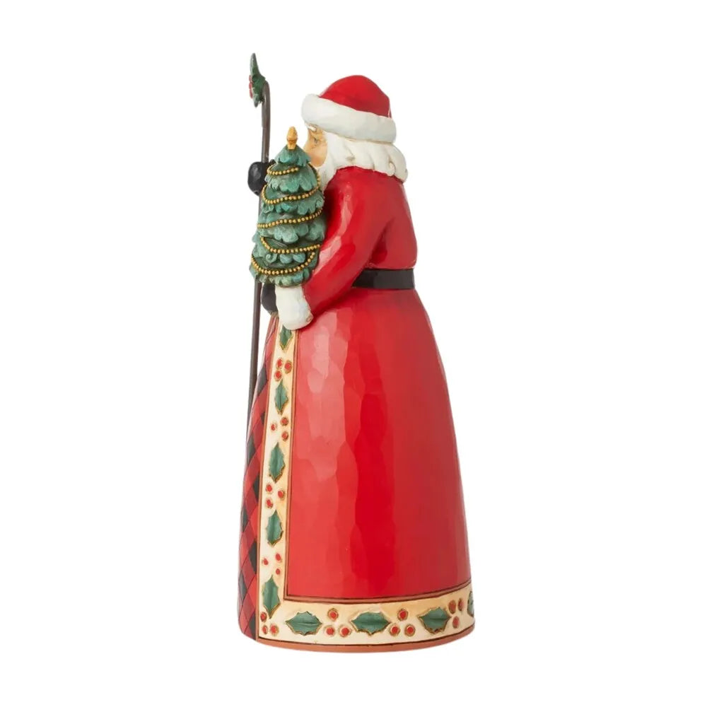 Opposite side view of Santa figurine in red coat with holly-detailed border, carrying a Christmas tree and holly-topped staff