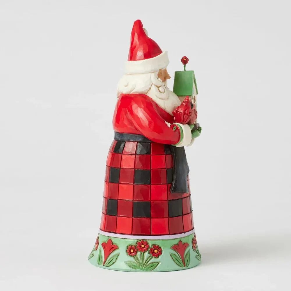 Side view of a Jim Shore Santa figurine in a red and black check robe holding a birdhouse, on a green floral-detailed base