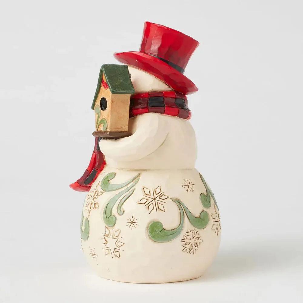 Opposite side view of a Jim Shore snowman figurine with buffalo check scarf cradling a cardinal and birdhouse, on a snowflake-detailed body